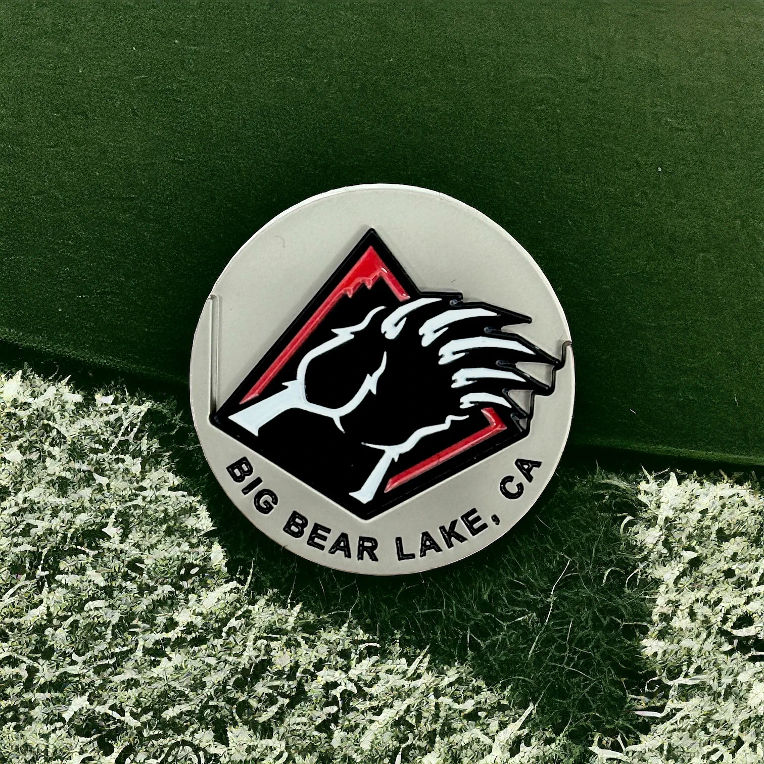 Silver golf ball market with Big Bear Lake, CA words at the bottom and a bear blaw removable ball marker in black, red, and white.